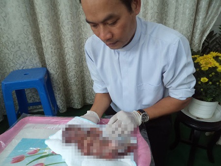 Linh mục Nguyễn Văn Tịch đang tắm rửa cho một thai nhi